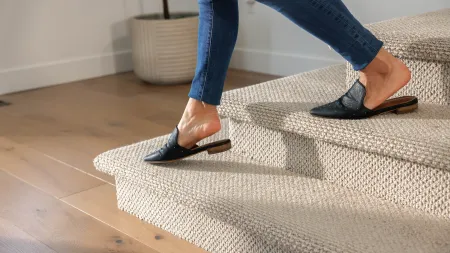 a person's feet in black sandals on a tile floor