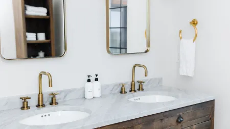 a bathroom with two sinks, mirrors over the sink, white hand towel, all accumulating and shedding dust in the bathroom