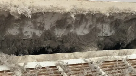 Close-up of dirty HVAC vent filled with dust and allergens, highlighting poor air quality.