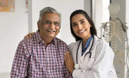 Smiling female doctor with stethoscope embraces senior male patient in medical office with skeleton model.