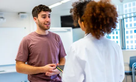 Young man talking to a female doctor in a bright medical office during a consultation session.