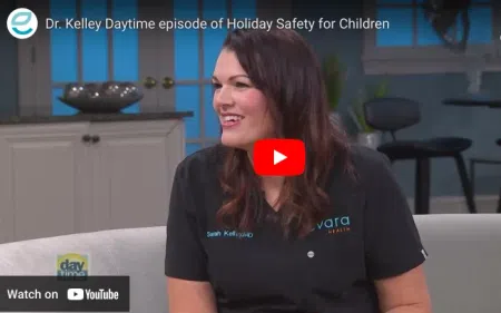 Dr. Kelley smiling during a daytime TV interview about holiday safety for children in a cozy studio setting.