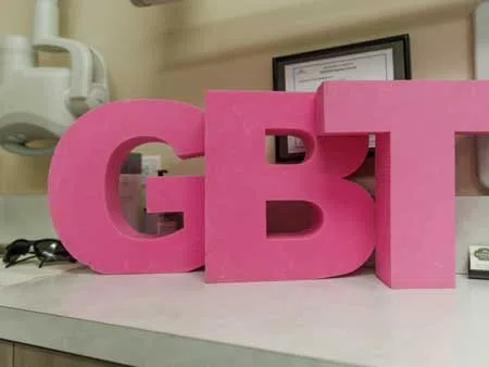 Large pink letters spelling GBT placed on a white countertop in indoor setting.