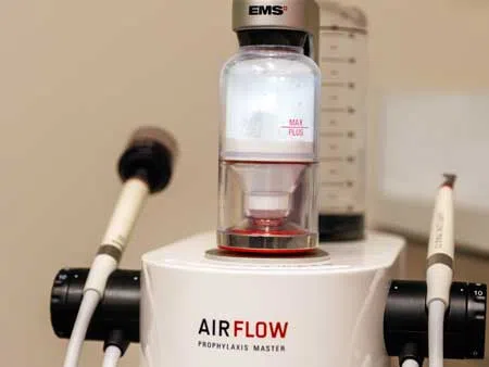 Close-up of AIRFLOW Prophylaxis Master dental equipment with EMS branding and attached handpieces.