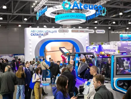 Crowded trade show booth of Ateuco featuring warehouse automation technology and machinery with attendees interacting.