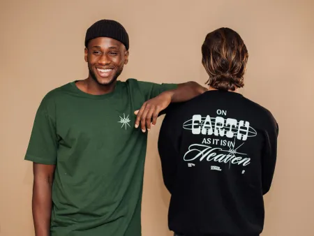 Two men modeling casual streetwear with printed designs, one smiling in green tee, other showing text on black sweatshirt.