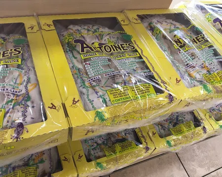 Stacked boxes of Antoine's King Cake with yellow packaging, showcasing traditional Mardi Gras colors and design.