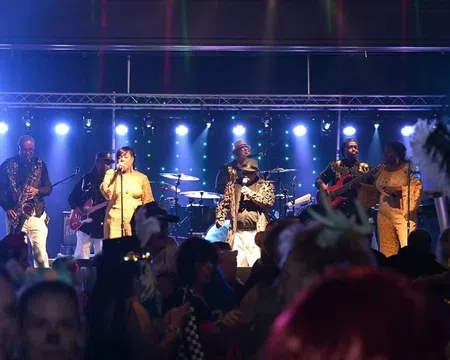 Live band performing on stage with vibrant blue lights and crowd enjoying the music at night event