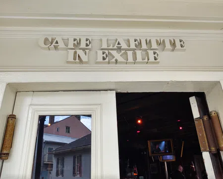 Entrance of Cafe Lafitte in Exile with white wooden doors and reflective glass showing buildings outside.