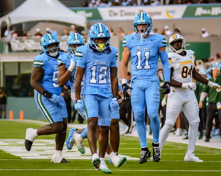 Tulane football players in blue uniforms celebrating on the field during a game against Southern University.