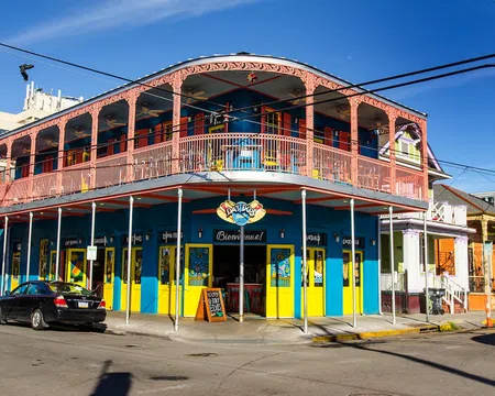Colorful two-story building with yellow and blue walls and pink balcony railing at street corner in sunny weather