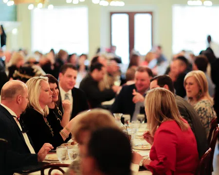 People enjoying a social gathering at a restaurant with conversations and dining in a warm, well-lit atmosphere.