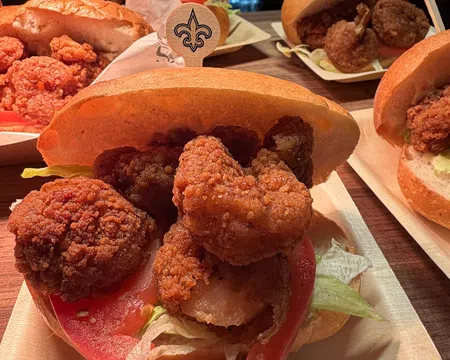 Close-up of fried shrimp po'boy sandwiches with lettuce and tomato on buns on wooden table