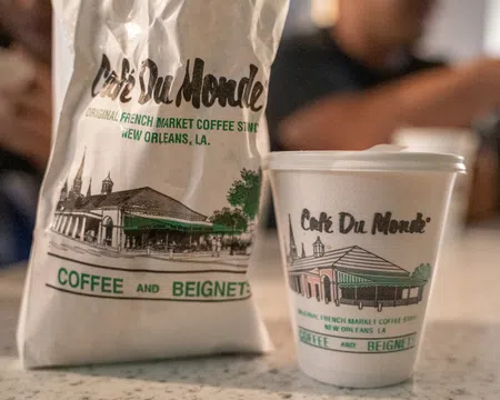Cafe Du Monde coffee cup and bag featuring French Market coffee shop branding from New Orleans, Louisiana.