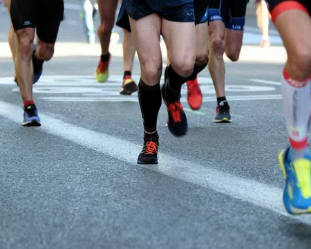 Close-up of runners' legs and feet in athletic shoes on a city road during a race event