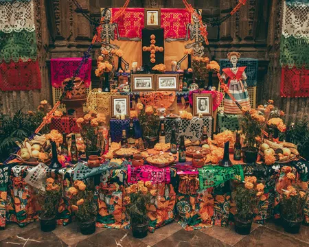 Traditional Mexican Day of the Dead altar decorated with marigolds, papel picado, photos, skeletons, and food offerings.