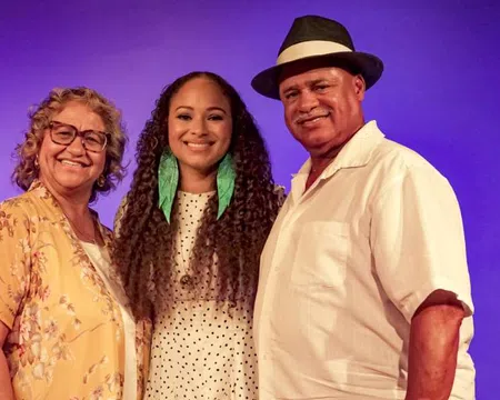 Smiling three generations family portrait with purple background and casual summer clothing