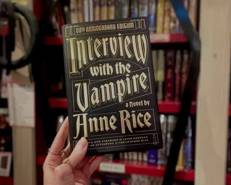Hand holding the 50th Anniversary Edition of Interview with the Vampire by Anne Rice with overlaid text on the book cover.