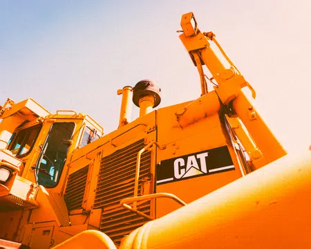 Close-up of a yellow Caterpillar bulldozer with visible CAT logo under bright sunlight.