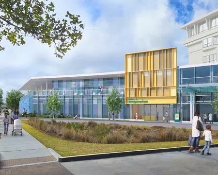 Modern imaging center with glass facade, yellow accent panels, landscaped front, and people walking outside.