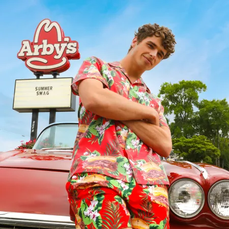 a person in a colorful dress standing next to a red car