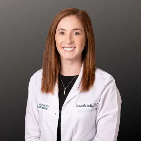 Smiling female healthcare professional wearing a white lab coat with name and Advanced Urology logo on gray background
