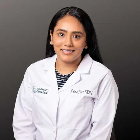 Female healthcare professional in white lab coat with Advanced Urology logo on gray background smiling