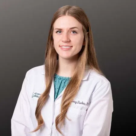 Professional portrait of a female healthcare provider wearing a white lab coat against dark background.