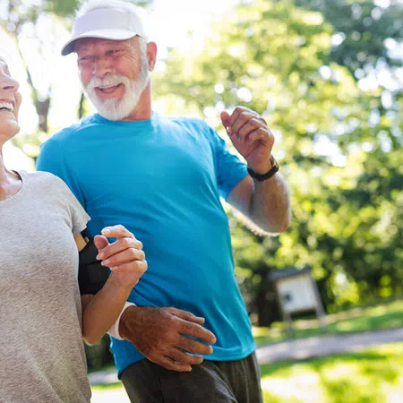 Active seniors jogging together in a sunny park, promoting fitness and joy in later life.