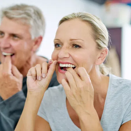 Couple demonstrating proper dental flossing technique for oral hygiene.