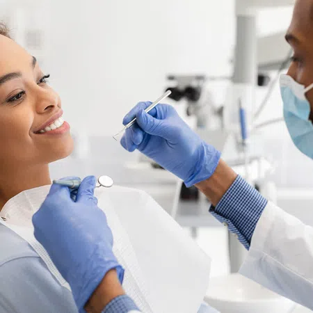 A dentist examining a smiling patient in a modern dental clinic setting.