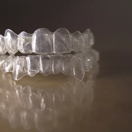 Close-up of transparent dental aligners on a reflective surface, showcasing their clear design.