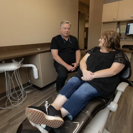 Dentist consulting with a female patient seated on a dental chair in a modern clinic room.