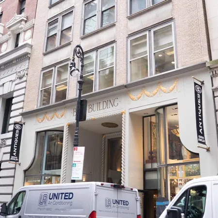 Exterior view of an antique store in a classic urban building with white vans parked outside on the street.