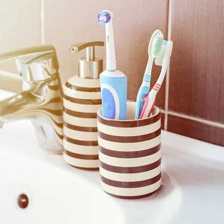 A modern bathroom setup featuring toothbrushes and a toothbrush holder by a sink.