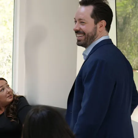 A man speaking confidently to a group of engaged women in a modern meeting room.