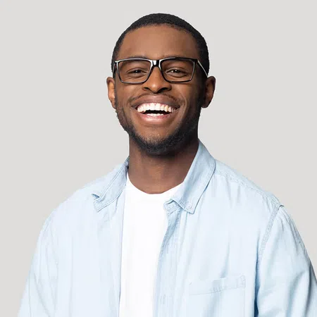 Smiling young man wearing glasses and a light blue shirt against a neutral background
