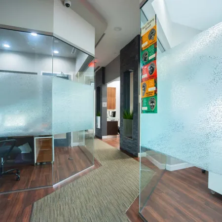 Modern office hallway with frosted glass consultation room doors and wood flooring in a professional setting