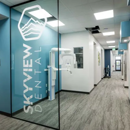 Modern dental office hallway with X-ray machine behind glass featuring Skyview Dental branding logo.