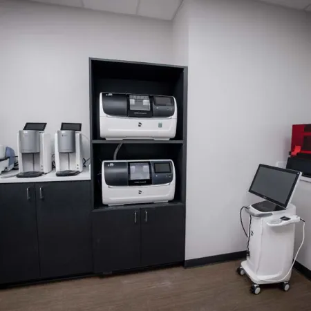 Modern laboratory room with advanced diagnostic machines and computer workstation on wheels