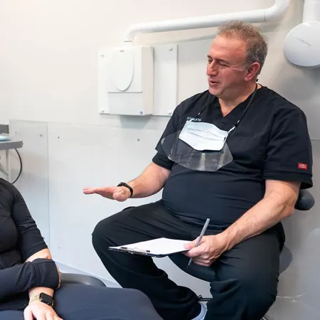 Dentist discussing dental treatment with female patient in modern dental office with x-ray on screen.