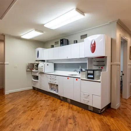 Modern white dental or medical sterilization room with autoclaves, cabinets, and wooden flooring under bright lights