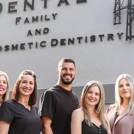 A friendly dental team stands in front of their family and cosmetic dentistry office.