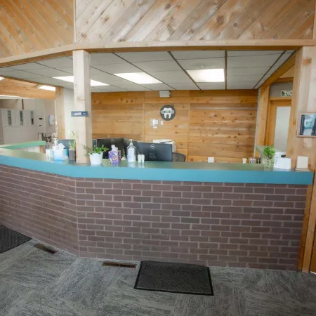 Reception area with blue countertop, brick front, wood-paneled walls, and office equipment in a cozy setting.