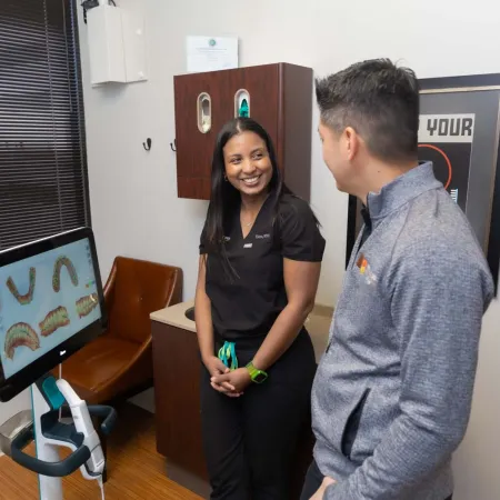 Dentist consulting patient with digital dental mold images on a screen in a modern clinic room