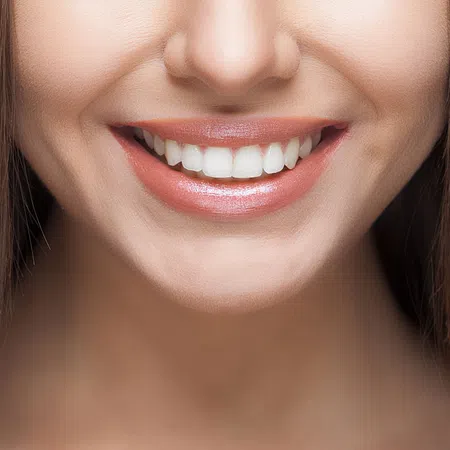 Close-up of a woman's smiling face highlighting bright, healthy teeth and glowing skin.