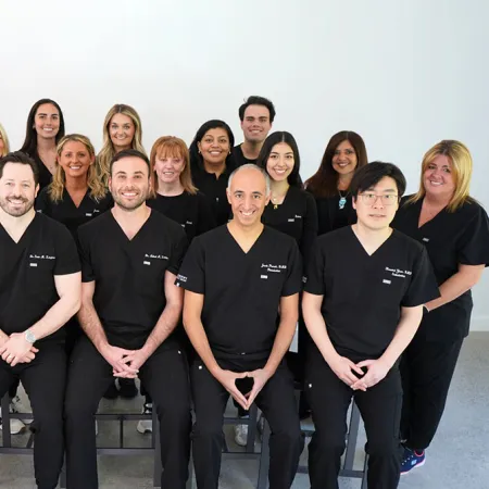 A team of healthcare professionals in black scrubs posing together for a group photo.