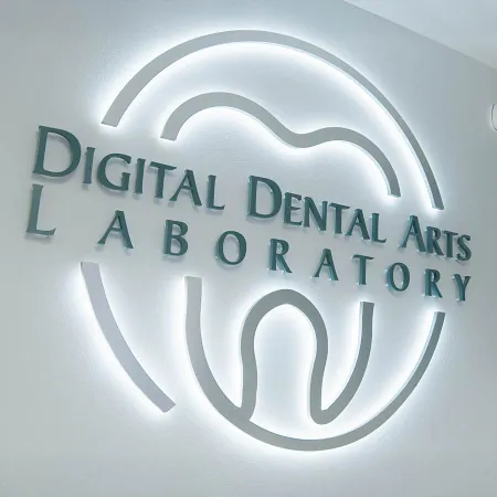 Illuminated wall sign of Digital Dental Arts Laboratory with a tooth-shaped logo in white light.