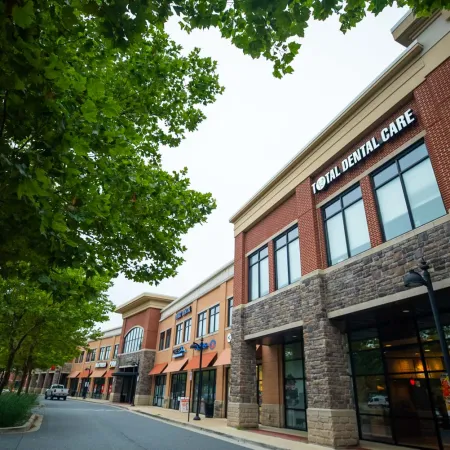 Street view of a modern shopping center with Total Dental Care and leafy trees lining the road under an overcast sky