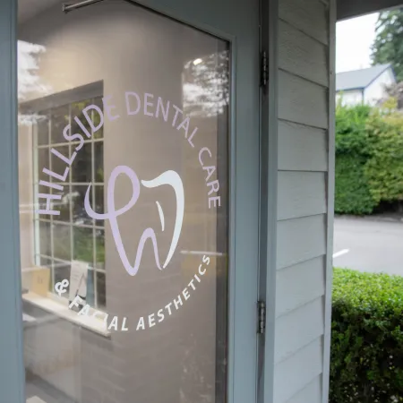 Glass door with Hillside Dental Care & Facial Aesthetics logo showing a stylized tooth design.